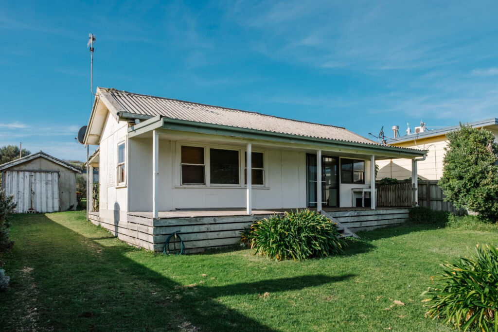 Exterior view of a detached single-story backyard accessory dwelling unit with a front porch and wooden deck.