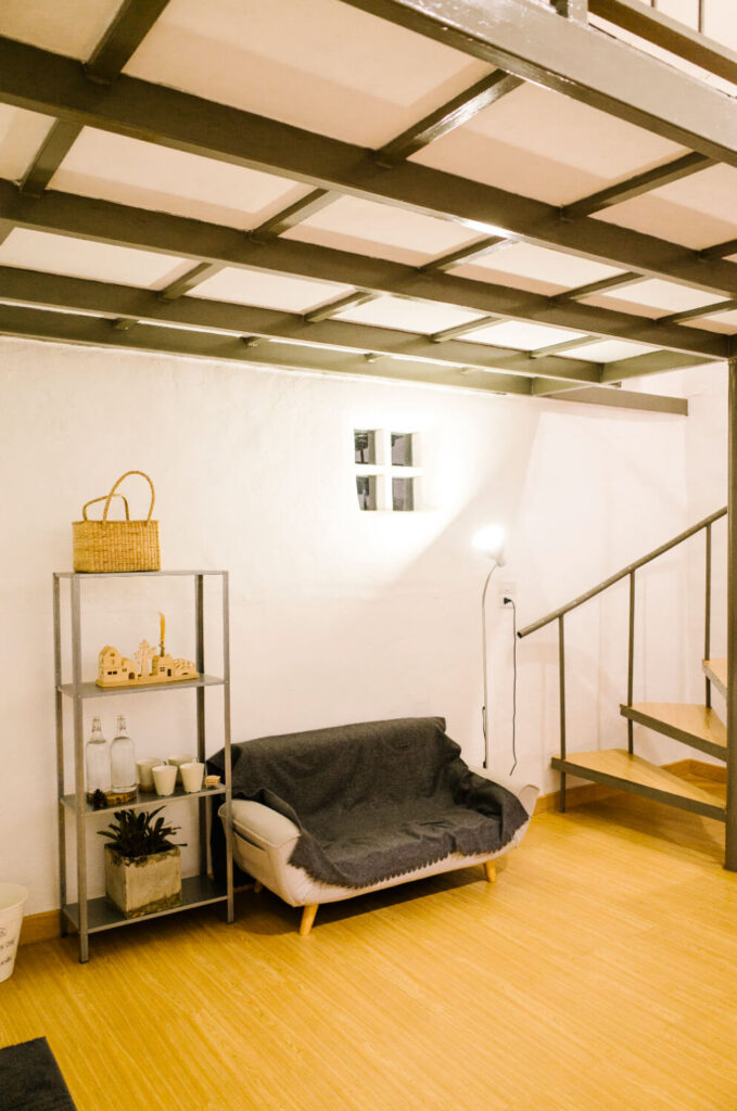 Interior conversion of a garage and basement into a living space with exposed steel beams and a spiral staircase for 303 ADU.