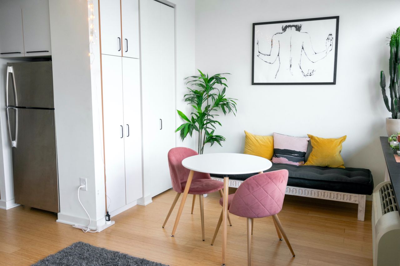 Compact open-concept interior of a small ADU featuring space-saving furniture, a dining set, and integrated kitchen storage.
