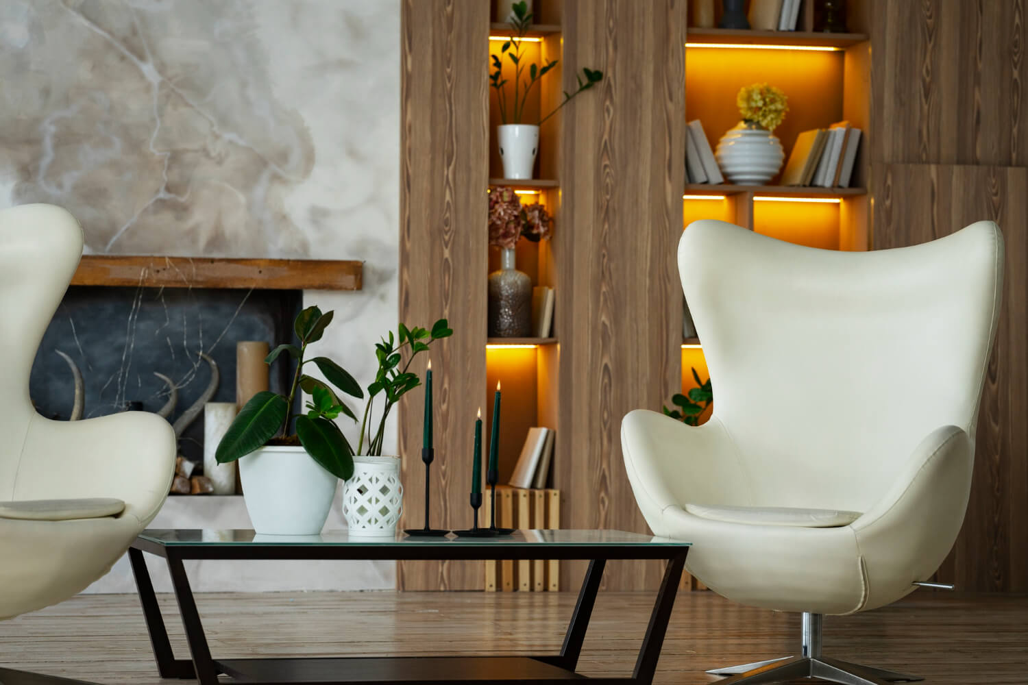 Modern living room interior with white egg chairs, a glass coffee table, and backlit wood shelving for a Colorado ADU design guide.